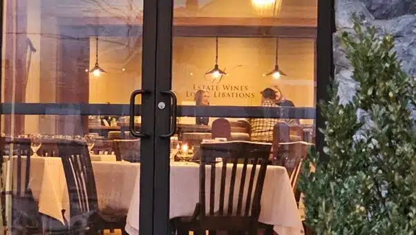 A view from the outside of people dining and enjoying wine inside Olde Mill Restaurant.