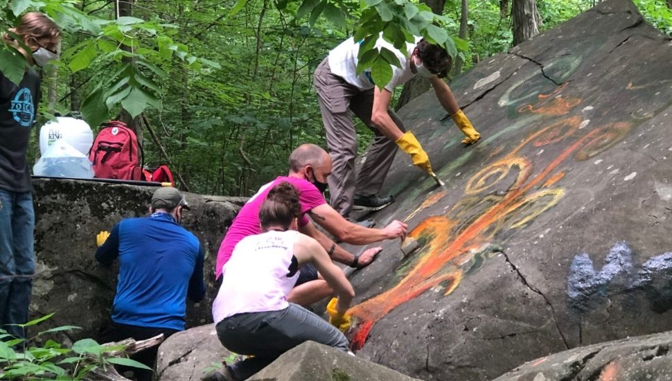 Volunteers from the Haycock Bouldering Coalition clean graffiti from rocks at Nockamixon State Park