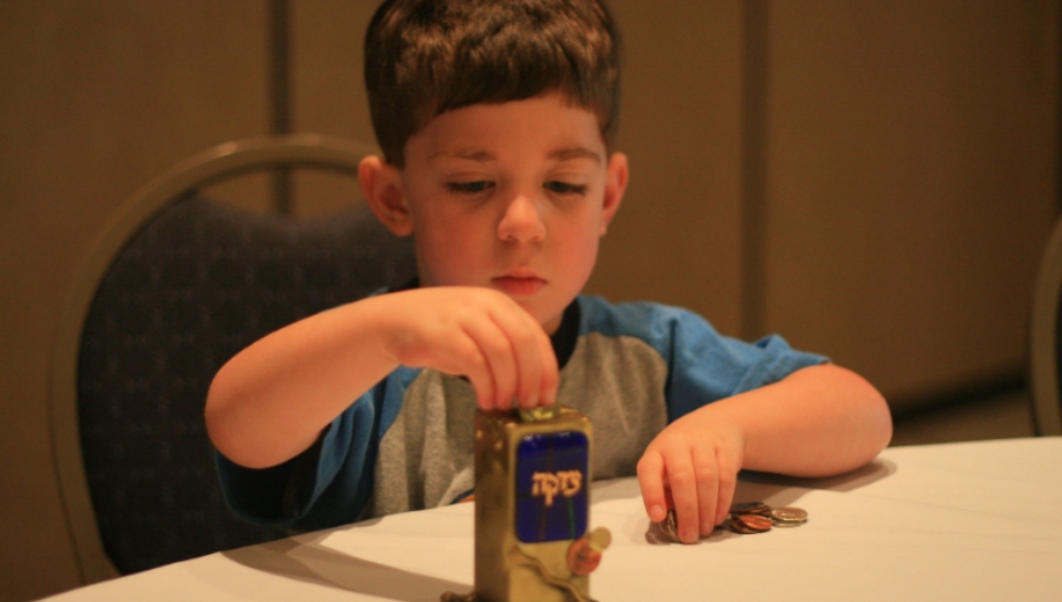little boy filling tzedakah box