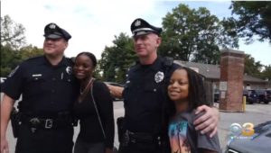 Police officers pose with a woman and child.