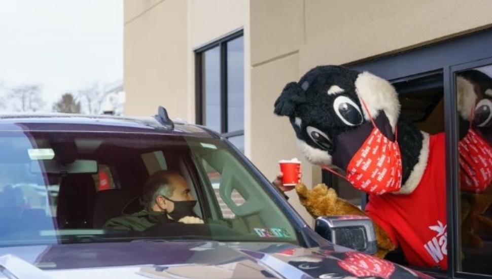 Wawa's mascot peeks through the drive-thru window at a Wawa store.