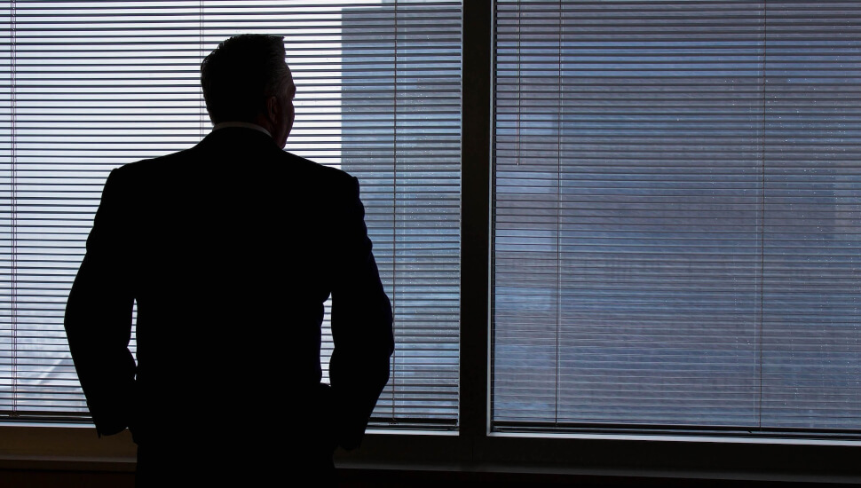 Business man standing by a window.