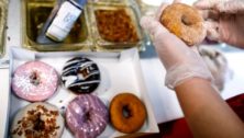 A worker customizes a box of Duck Donuts.