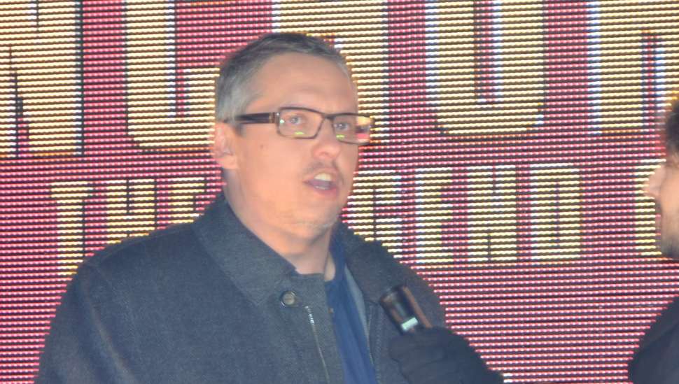 man in glasses in front of electric sign