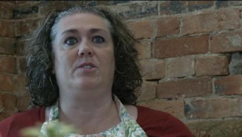 woman sitting by brick wall