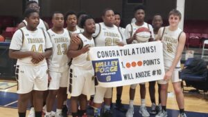 Will Anozie with his teammates holding a congratulatory sign on his 1,000 point cumulative score.