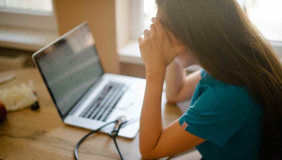 tired nurse at laptop