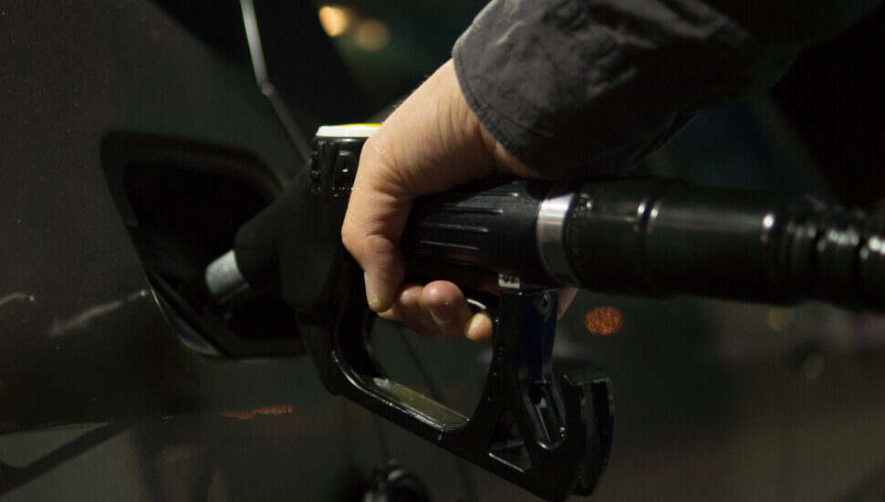 A hand pumping gasoline into a car