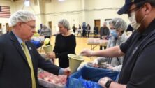 Neumann University President Dr. Chris Domes working with volunteers to fill food packages for Ukrainian refugees.
