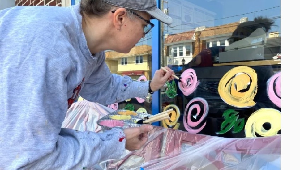 Becky O'Hara paints a window along Brookline Blvd.
