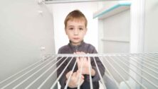 boy peering into empty refrigerator