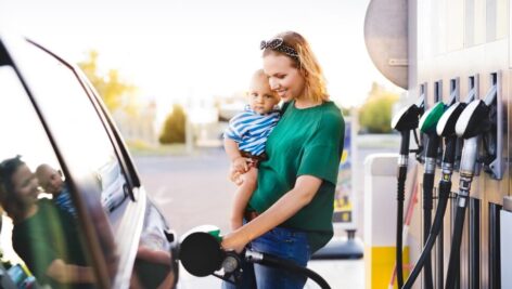 Woman holding a child pumping gas