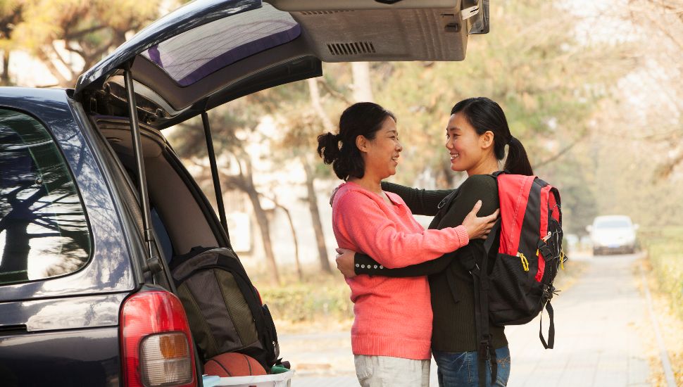 older woman with younger woman by a car
