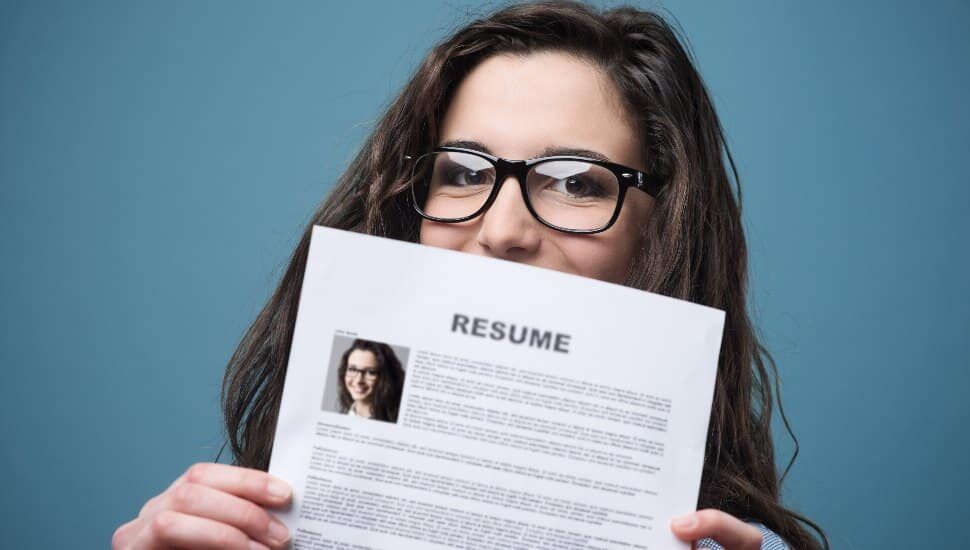 Young woman hiding behind her resume