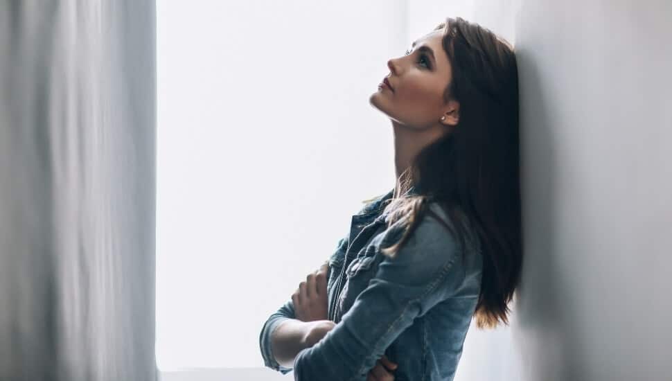 vulnerable woman leaning against a wall.