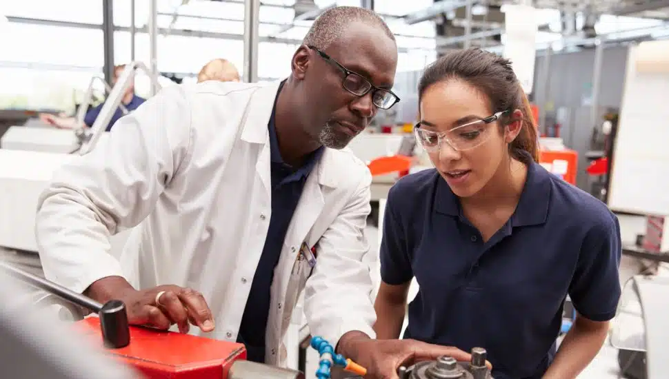man showing woman a piece of machinery