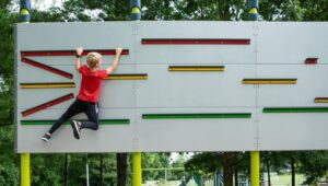 A boy works his way across an outdoor fitness board
