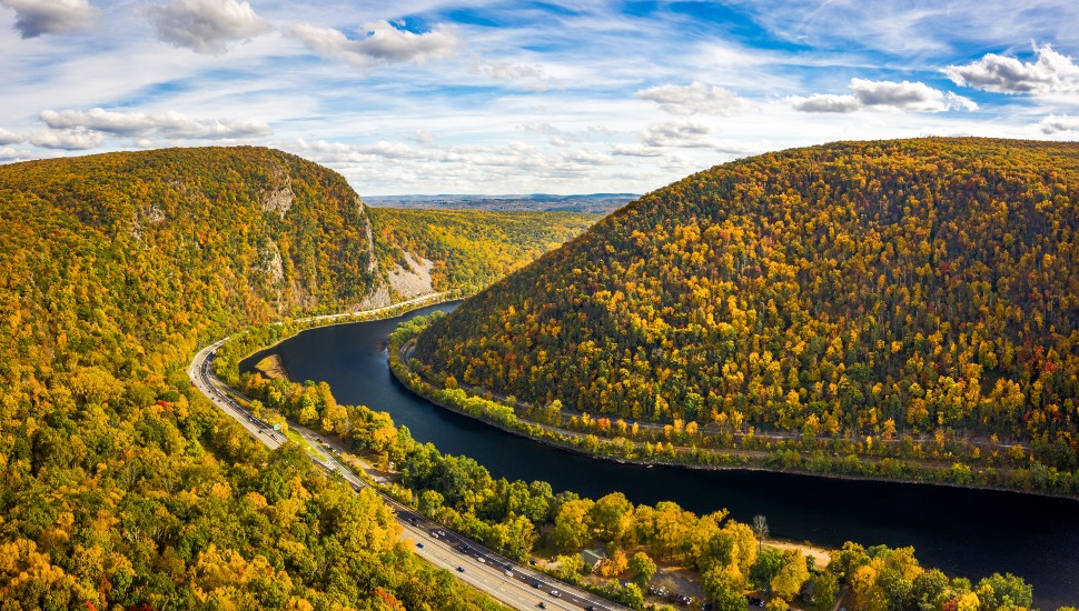 semi-aerial view of delaware river meanduring between two forested mountains