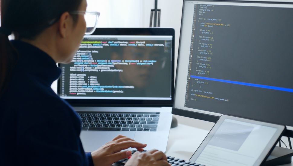 programmer, software engineer, IT support, wearing glasses working on computer to check coding in bugging system. Back view