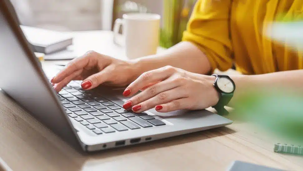 A woman typing on a laptop computer.