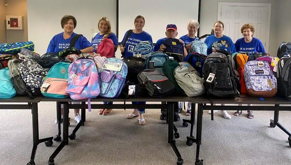 Several people lined up with donated backpacks