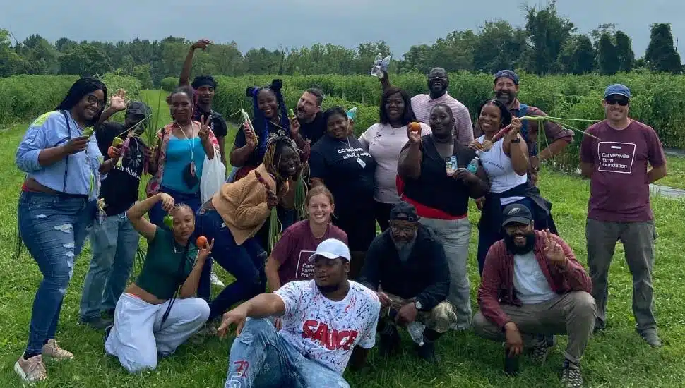 Several people sittting in a field at the farm