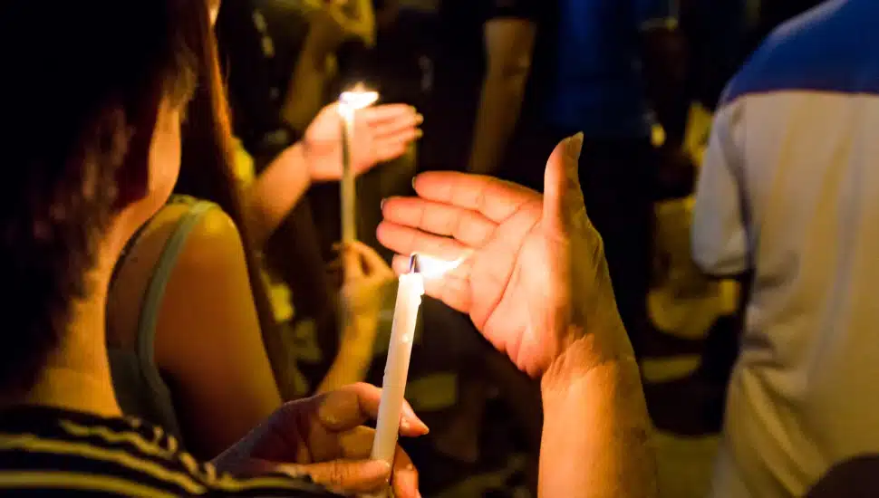 Several people holding candles at night time.