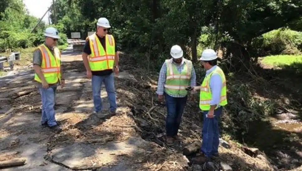 Safety works look at a road damaged by floods