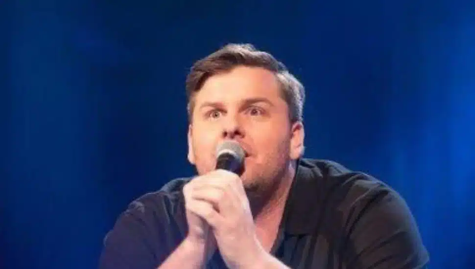 Comedian Tim Dillon in stage speaking into a microphone