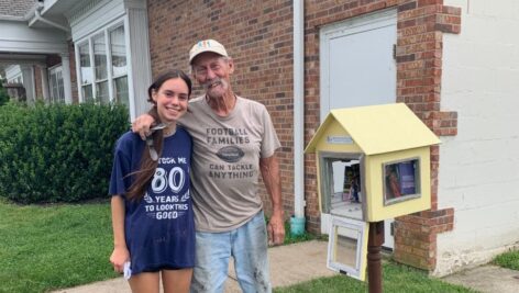 Aubrey Williams and her grandfather stand next to a little library