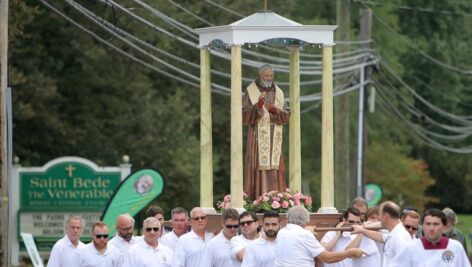 A statue of Padre Pio being walked through the streets