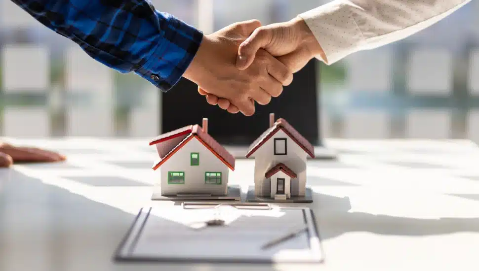 Real estate agents shake hands after the signing of the contract agreement is complete.