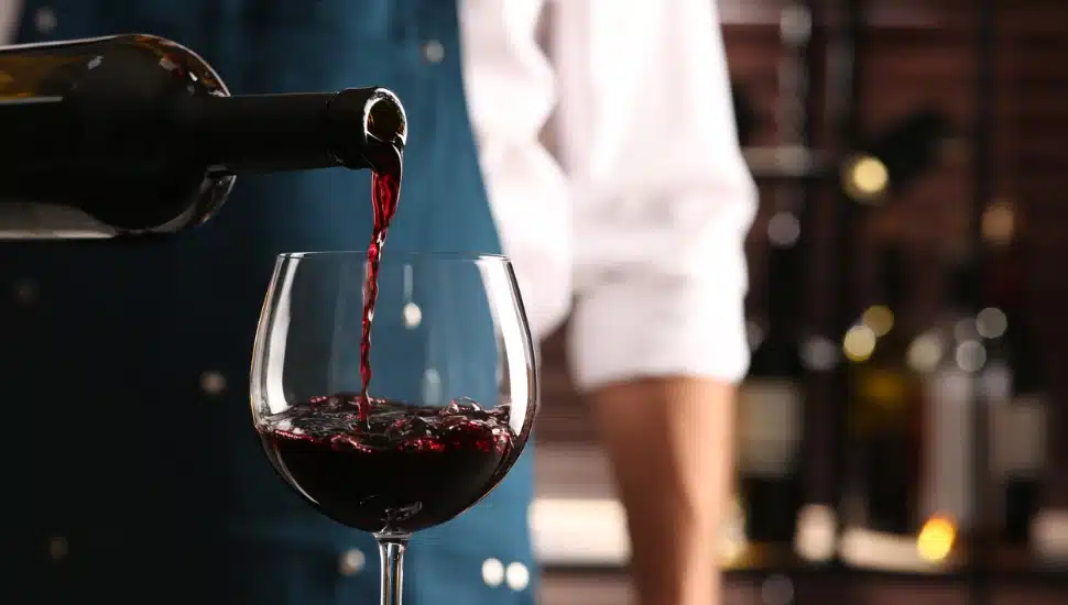 A sommelier pouring a glass of red wine