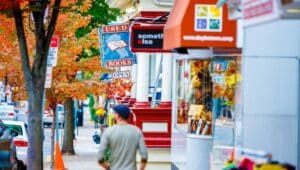 person from behind on doylestown sidewalk with storefronts and tree in autumn