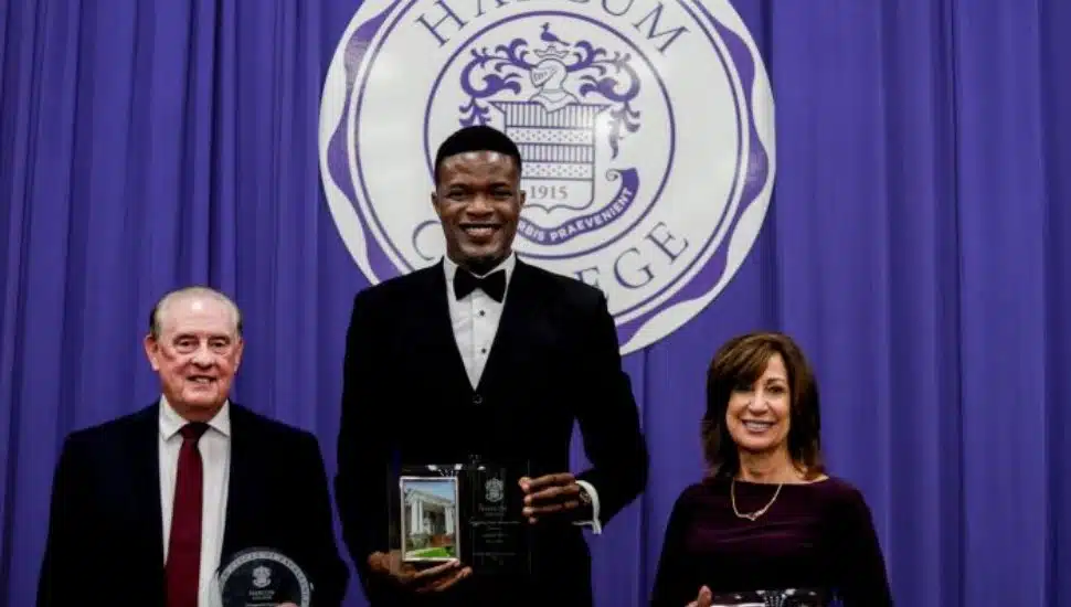 From left: Denis C.Boyle, Augustine Okosun ’07, and Karen Naylor ’92 standing in front of Harcum College logo