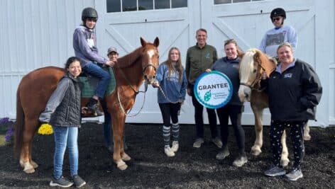 Surrounded by program horses, clients and staff, Foundations Community Partnership’s CEO Tobi Bruhn (center), presented a grant to Ivy Hill Therapeutic Equestrian’s new Executive Director Susanne McMahon (right).