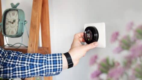 A man's hand adjusting a thermostat
