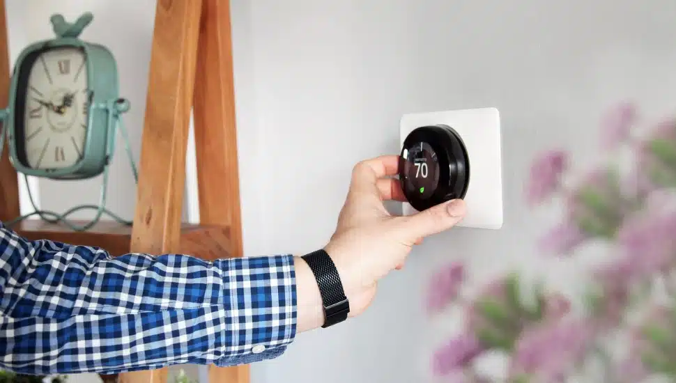 A man's hand adjusting a thermostat