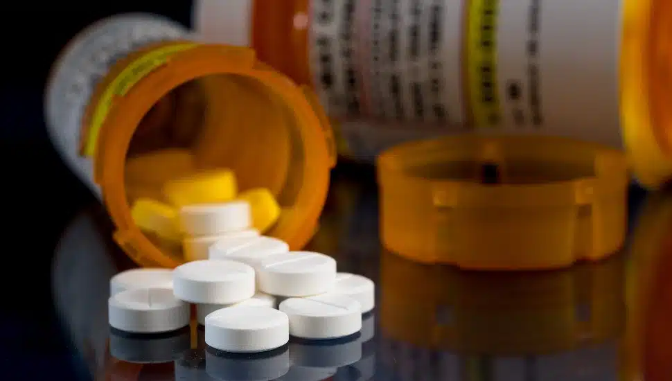 pill bottles lying down uncapped with pills laying out beside it