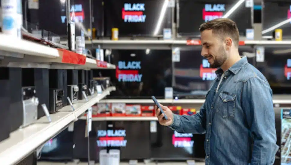 A man browsing electronics with Black Friday signs surrounding him.