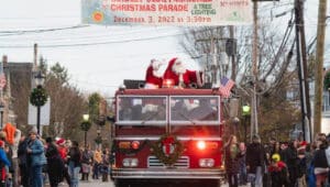 Yardley township Christmas parade in 2022 santa and Mrs. Claus on firetruck under banner