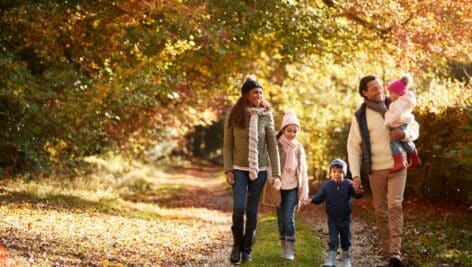Front View Of Family Enjoying Autumn Walk In Countryside