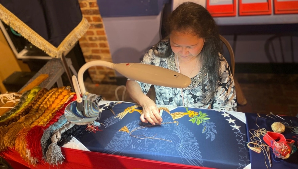 Hand embroiderer from the Defense Logistics Agency (DLA) Troop Support manufacturing a flag.