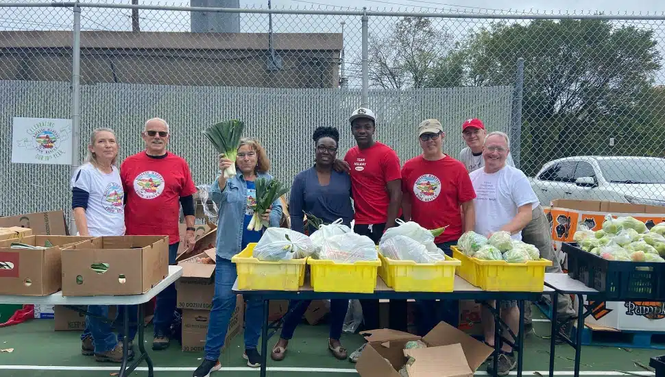 Rolling Harvest Food Rescue volunteers standing behind tables full of produce