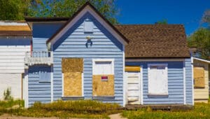 abandoned and boarded up blue American style home exterior