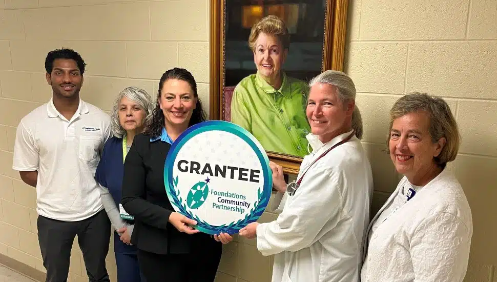 Members of the Ann Silverman Community Health Clinic team, posing in front of a portrait of Ann Silverman, recently received a Capital Improvement Grant from FCP. From left to right: Pre-med student volunteer Amal Thalody, Clinic Coordinator Susan Hartsock, Executive Director Meri L. Gaumond, Dr. Amy Ruesch, Nurse Practitioner, and Nurse Patricia Heckenberger.