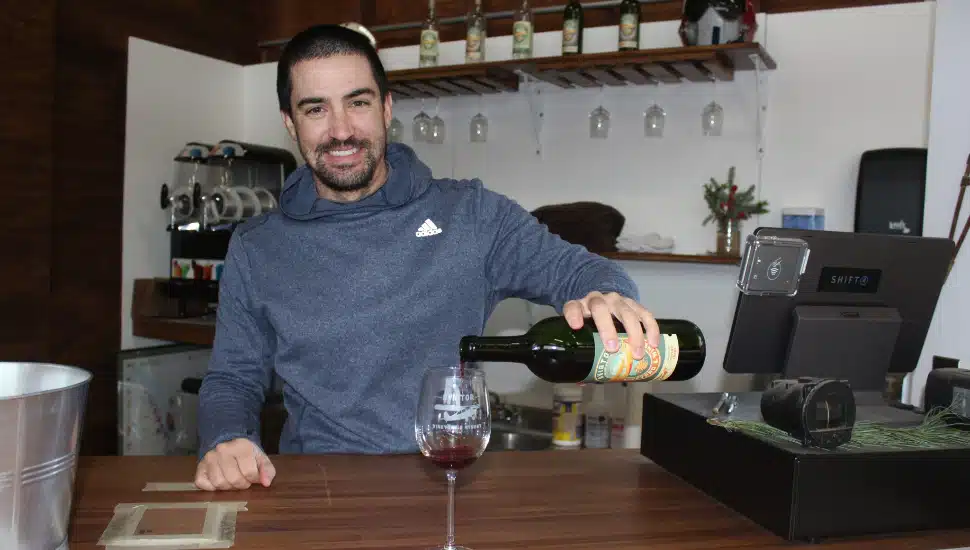Chris Burns pouring wine in glass behind bar