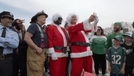 Peyton Manning dressed as Santa poses with other people