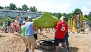 Volunteers from the community help assemble a piece of playground equipment.