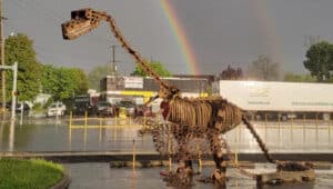dinosaur sculptures with rainbow in background